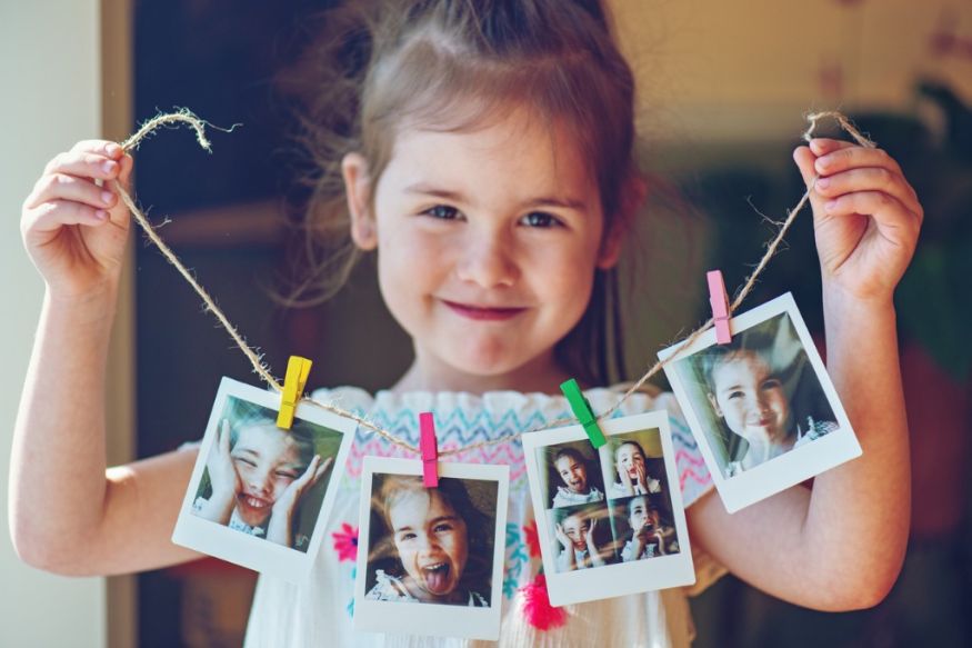 Young girl holding up photos